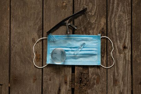 glass globe and ampoule with medicine and doctor s glasses on a medical mask on a table