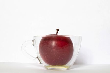 red apple in a transparent glass cup on a white backgroundの写真素材