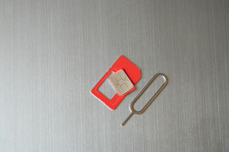 a sim card and a paper clip for opening a slot for a sim card lies on a gray steel background