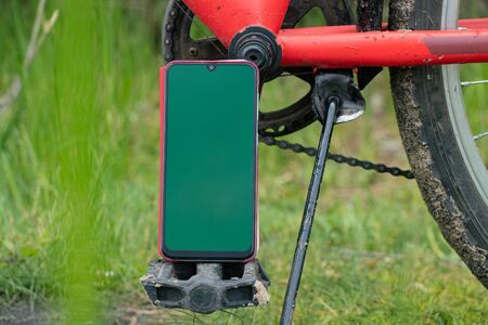 phone with a green screen stands on a bicycle on the street for a walkの写真素材