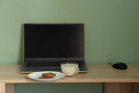 laptop with green screen yogurt with cookies on a table in a room at homの写真素材