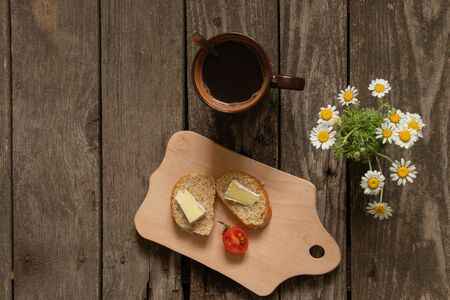 hot black tea and white bread with butter and cheese on an old tableの写真素材