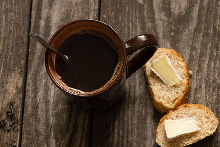 hot black tea and white bread with butter and cheese on an old tableの写真素材