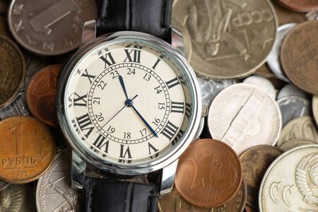 collection of coins from around the world at different times as a background and men's watchesの写真素材