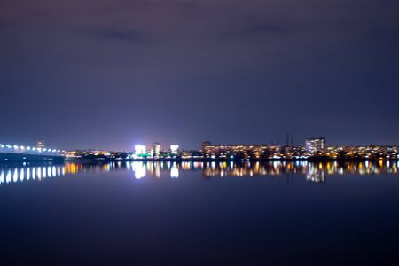night skyscrapers and a bridge in the reflection of the Dnieper in the city of Dnieper in Ukraineの写真素材