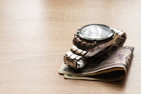 dollars invested in men's watches lie on a table in the sunlightの写真素材