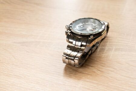 men's watch lying on a table in the sunlightの写真素材