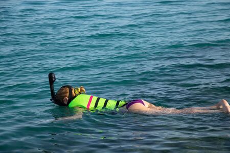 girl diving in the red sea in egypt lies on the water in a mask
