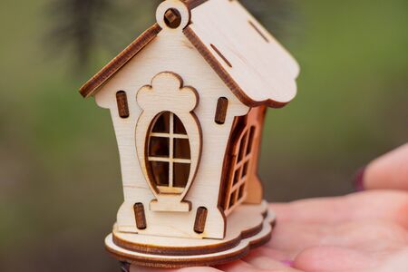 Girl holds a small wooden house outdoorsの写真素材