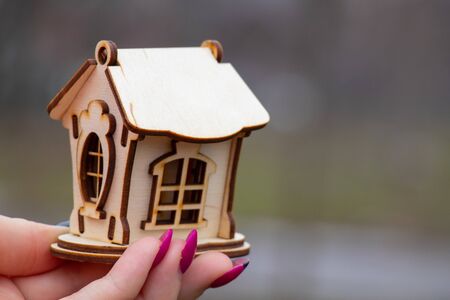 Girl holds a small wooden house outdoors in the afternoon closeupの写真素材