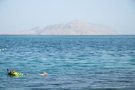 girl diving in the red sea in egypt lies on the water in a maskの写真素材