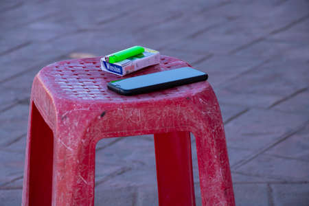 Sharm El Sheikh, Egypt - December 18, 2019. On a bench on the street are a pack of cigarettes and a telephone.のeditorial素材