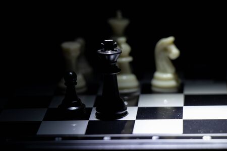 chess pieces on a chessboard in a dark room illuminated by a lanternの写真素材