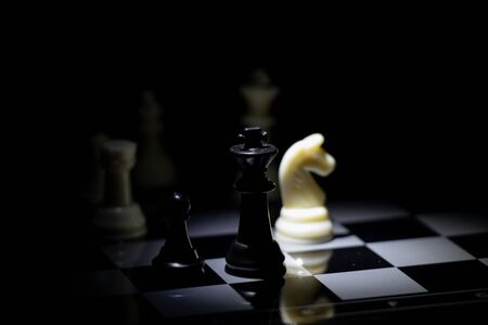 chess pieces on a chessboard in a dark room illuminated by a lanternの写真素材
