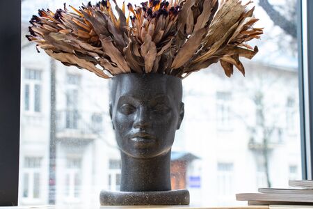 vase in the shape of a person's face with a bouquet of dried exotic flowersの写真素材