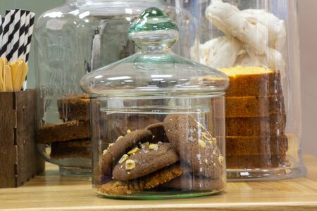 a glass jar of chocolate chip cookies stands on a tableの写真素材