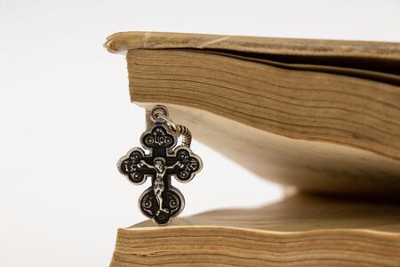silver christian cross and old book on a white backgroundの写真素材