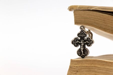 silver christian cross and old book on a white background