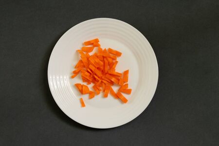 chopped carrots julienne on a plate on a dark backgroundの写真素材