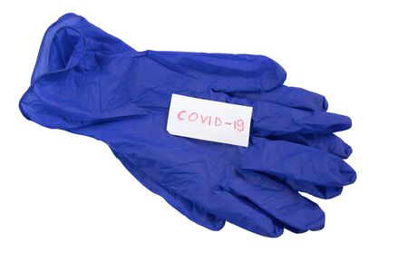 COVID-19 is written on a piece of paper and lies on a blue medetsinsky glove on a whiteの写真素材