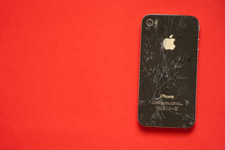 Ukraine, Dnipro - April 04, 2020. An old broken iPhone 4 lies on an orange background close-up.のeditorial素材