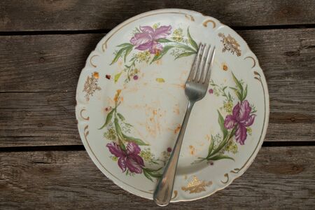 dirty plate with a fork on a wooden tableの写真素材