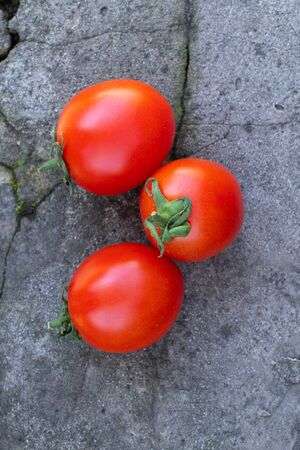 red cherry tomatoes on a wooden old chopper in daylight close-upの写真素材