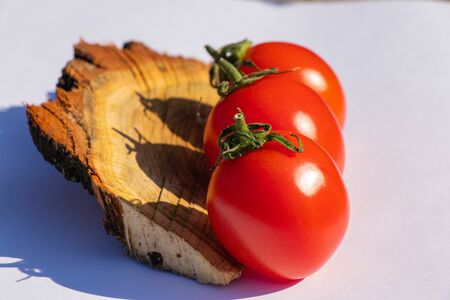 red cherry tomatoes on a wooden old chopper in daylight close-upの写真素材