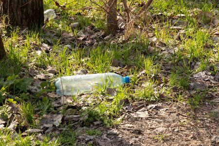a plastic bottle lies on grass in nature thrown away like garbageの写真素材