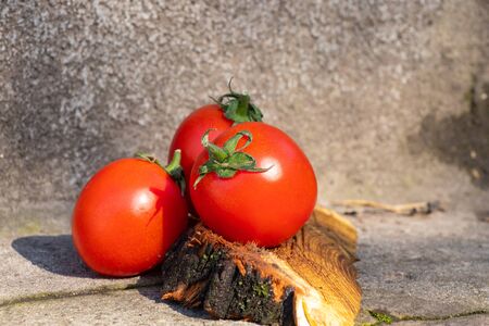 red cherry tomatoes on a wooden old chopper in daylight close-upの写真素材
