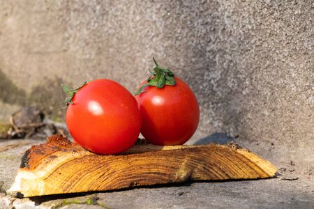red cherry tomatoes on a wooden old chopper in daylight close-upの写真素材
