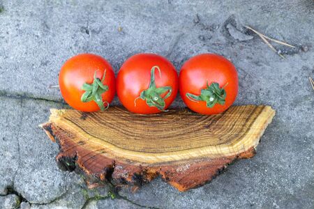 red cherry tomatoes on a wooden old chopper in daylight close-upの写真素材
