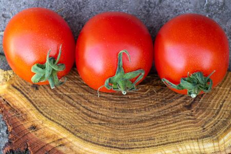 red cherry tomatoes on a wooden old chopper in daylight close-upの写真素材