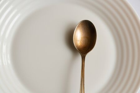 white plate and teaspoon on an isolated background close-upの写真素材