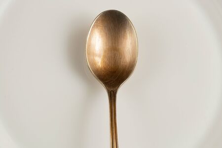 white plate and teaspoon on an isolated background close-upの写真素材