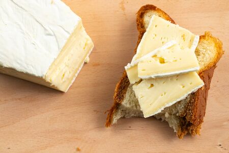 homemade bread and a piece of brie cheese on a wooden board in daylightの写真素材