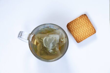 transparent glass cup of tea herbal tea in a bag on a white background view from the top and cookiesの写真素材