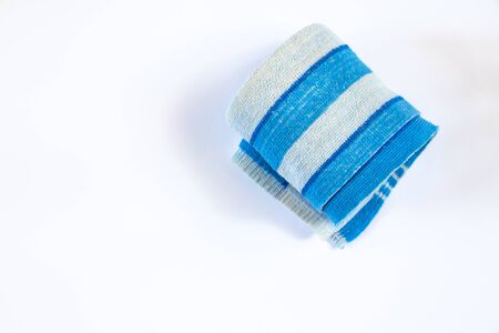 blue terry striped towel rolled up on a white backgroundの写真素材