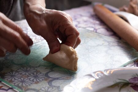 old grandmother's hands are making pies on the tableの写真素材