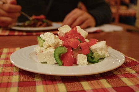 salad with vegetables and cheese on a white plate in the evening in a restaurantの写真素材