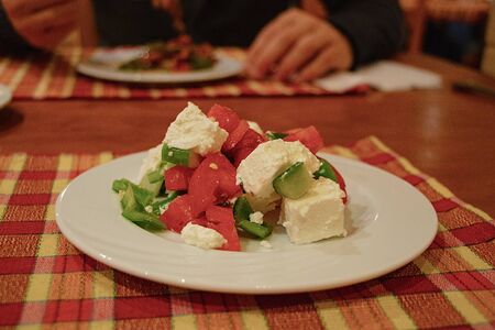 salad with vegetables and cheese on a white plate in the evening in a restaurantの写真素材