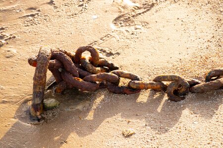 rusty old chain fastened to a concrete wall in the streetの写真素材