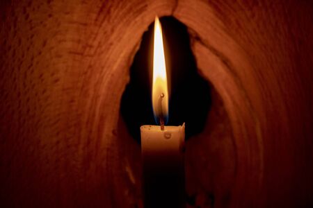 lighted candle stands in a dark roomの写真素材
