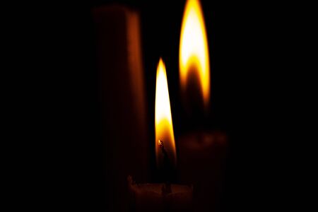 lighted candle stands in a dark roomの写真素材