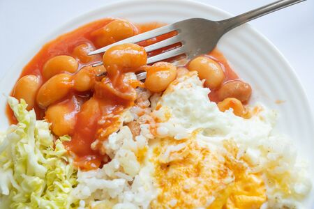 fried eggs with beans in tomato and salat with cabbage on a plate on an isolated background for lunch without meaの写真素材