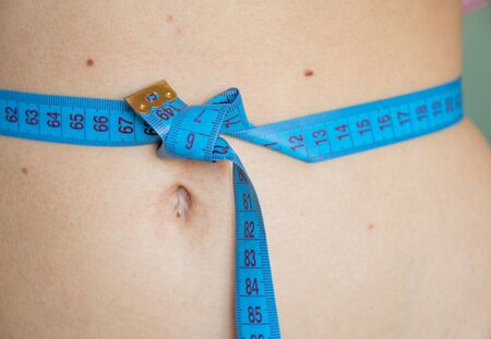 skinny belly of a young girl with a centimeterの写真素材