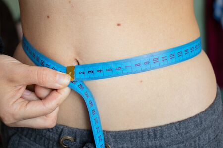 skinny belly of a young girl with a centimeterの写真素材