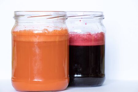 freshly squeezed carrot and beetroot juice in banks on a table in the morningの写真素材