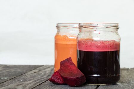 freshly squeezed carrot and beetroot juice in banks on a table in the morningの写真素材