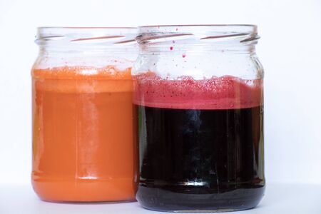 freshly squeezed carrot and beetroot juice in banks on a table in the morningの写真素材
